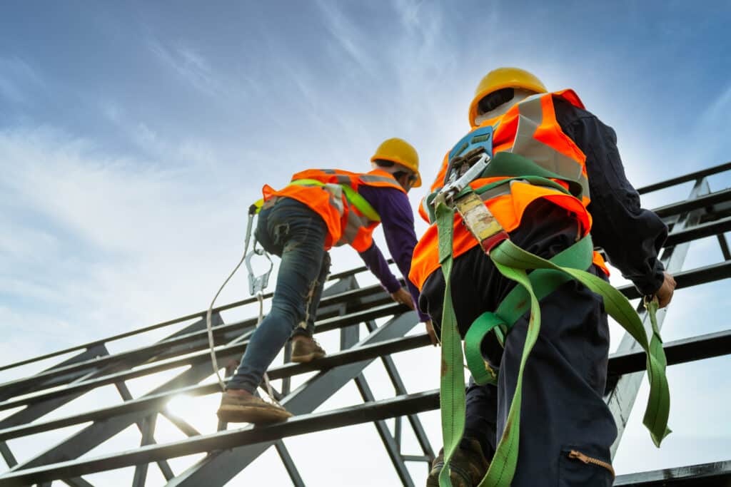 Construction crew in full safety gear, working at a jobsite. Payroll outsourcing has freed up time for management to be more active in operations.