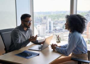 People sitting at a desk, in a Highrise office, discussing expense management software.