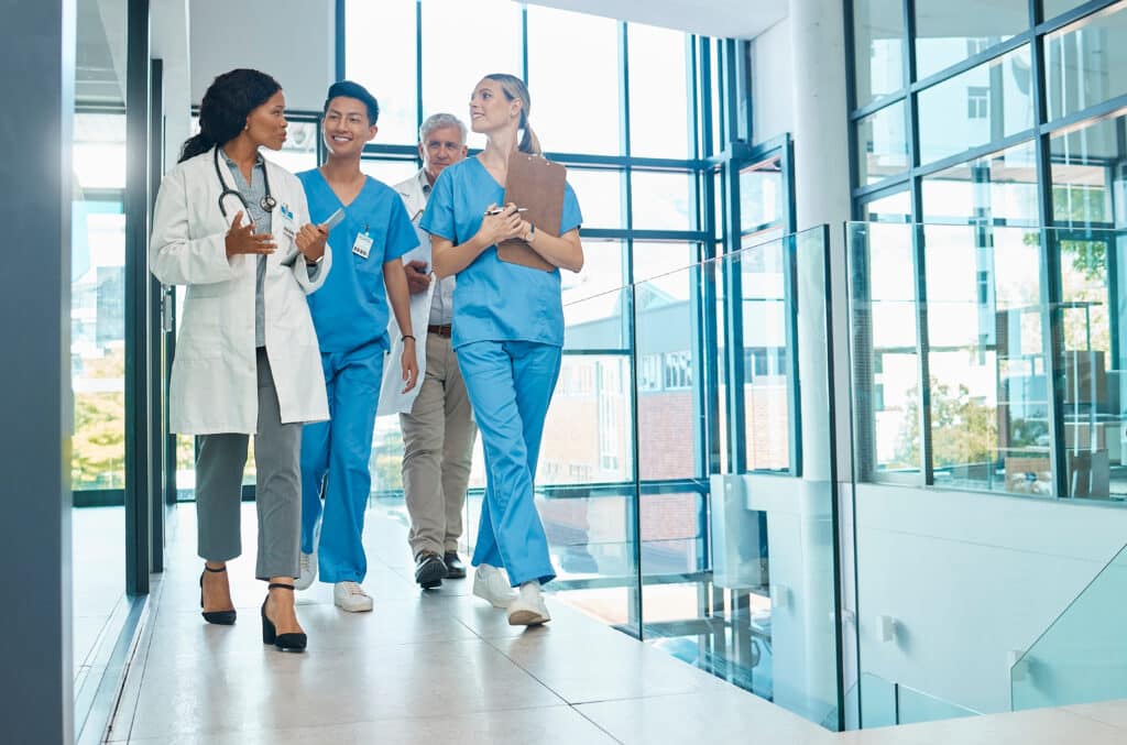 Team of doctors and nurses walking together discussing payroll services for healthcare, as well as upcoming open-heart surgery.